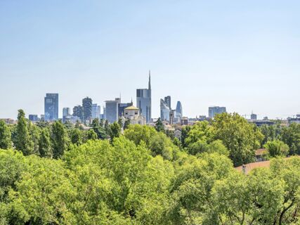 View of Milan skyscrapers and a church dome with surrounding green trees under a clear sky for B&B Hotel Milano Cenisio Garibaldi