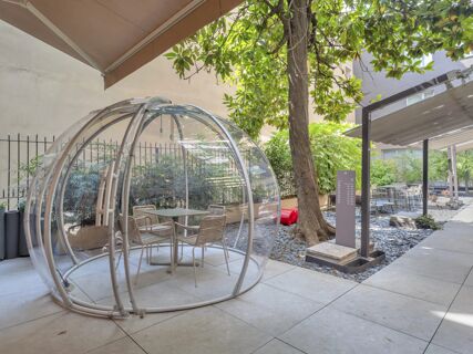 Outdoor seating area at B&B Hotel Milano City Center Duomo with a transparent dome structure, chairs, tables, and greenery
