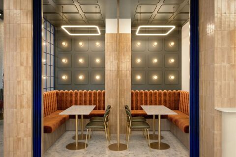 Two seating areas with orange velvet banquettes, green chairs, marble tables, and decorative lighting at B&B Hotel Milano Duomo Velasca