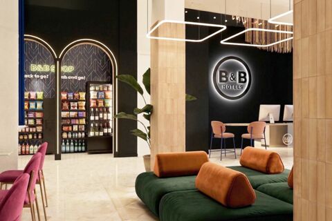 Modern B&B Hotel Milano Duomo Velasca lobby with green and orange sofas, pink chairs, and a snack shop under arched lighting