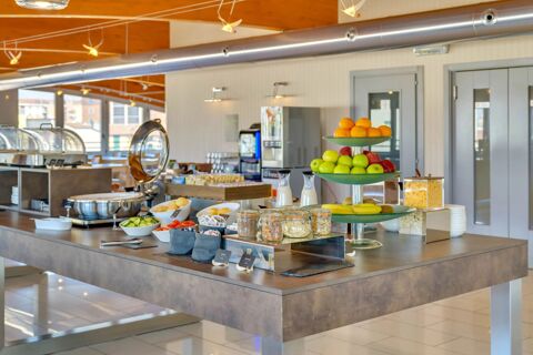 Buffet area with fresh fruit, cereals, bread rolls, vegetables, and milk bottles in the breakfast room at B&B Hotel Milano La Spezia
