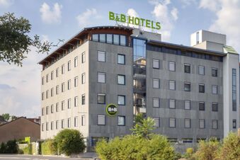 Modern multi-story building with numerous windows and large green B&B Hotels signage on top at B&B Hotel Milano La Spezia