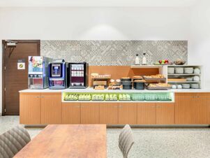 Breakfast buffet with coffee machines, pastries, fruits, milk bottles, plates, and cups in B&B Hotel Milano San Siro dining area