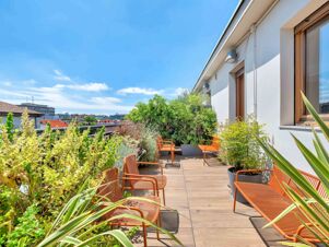 Outdoor terrace with orange metal chairs, green plants, and a clear blue sky at B&B Hotel Milano Sant'Ambrogio