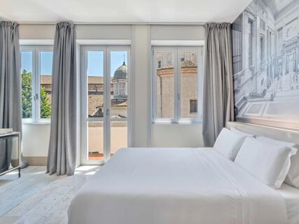 Bright hotel room at B&B Hotel Milano Sant'Ambrogio with large windows, gray curtains, white bed linens, and a cityscape mural on the wall
