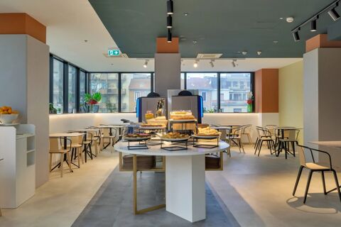 Modern breakfast area at B&B Hotel Milano Sesto Marelli with round table displaying assorted pastries and stocked beverage dispensers