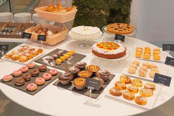 Variety of pastries, croissants, donuts, cakes, and muffins displayed on a round table at B&B Hotel Fabriano Janus