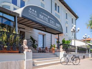 Entrance of B&B Hotel Pesaro Des Bains with a covered awning, stone sphinx statues, stairs, and parked bicycle outside