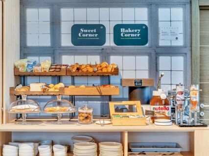 Breakfast buffet with pastries, bread, jam, Nutella, tea bags, and juice dispensers at B&B Hotel Torino Orbassano