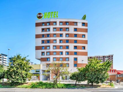 Building with white and brown horizontal stripes and many windows topped with a large B&B Hotel Torino Orbassano sign