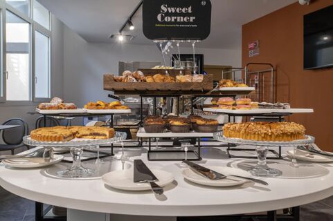 Various pastries and baked goods displayed on white plates and wooden trays at the Sweet Corner in B&B Hotel Sassari