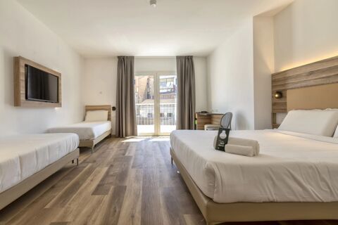 Hotel room with two single beds and one double bed, wood flooring, wall-mounted TV, desk, and balcony at B&B Hotel Sassari