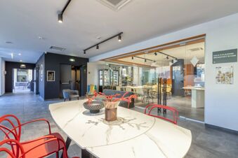 Interior view of the seating area and breakfast room with glass doors at B&B Hotel Sassari featuring red chairs and modern decor
