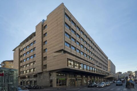 Large multi-story building with beige exterior and many windows on a city street, showing B&B Hotel Catania City Center sign