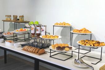 Breakfast buffet with assorted pastries, bread, muffins, fresh fruit, cereal jars, and condiments at B&B Hotel Catania City Center