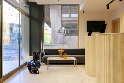 Modern hotel lobby interior with a curved wooden reception desk, dark sofa, marble table, and decorative vases at B&B Hotel Catania City Center