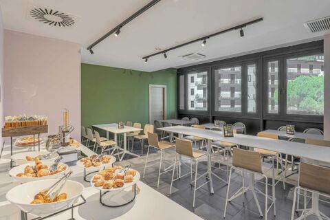 Dining area with tables, chairs, large windows, and a breakfast buffet at B&B Hotel Prato City Center