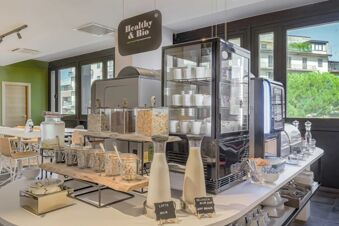 Breakfast buffet area with cereals, milk bottles, coffee machine, and glass containers at B&B Hotel Prato City Center