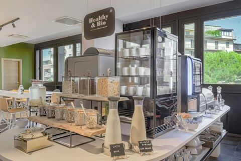 Breakfast buffet area with cereals, milk bottles, coffee machine, and glass containers at B&B Hotel Prato City Center