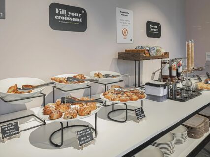 Buffet setup with croissants, pastries, various jams, crackers, and waffle cones at B&B Hotel Prato City Center breakfast area