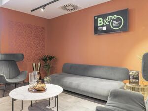 Modern lounge area with gray sofas, black armchairs, decorative vases on a marble table, and a TV screen at B&B Hotel Prato City Center