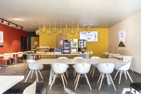 Dining area with white chairs and tables, modern pendant lights, coffee machine, and buffet at B&B Hotel Bolzano