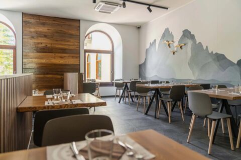Dining area with wooden tables, grey chairs, large arched windows, mountain mural, and bird decorations in B&B Hotel Passo Tre Croci Cortina
