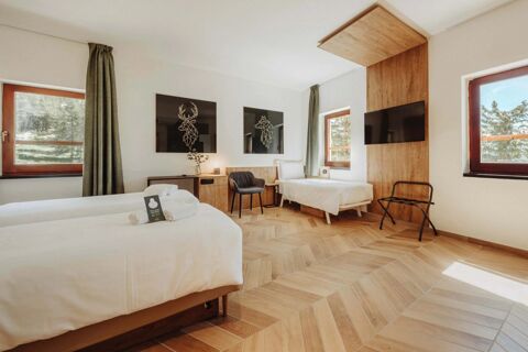 Bright guest room at B&B Hotel Passo Tre Croci Cortina with two single beds, wooden flooring, TV, chair, and windows with curtains