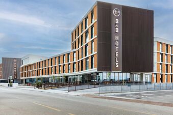 Modern curved low-rise building with brown and white exterior and large vertical sign displaying B&B Hotels at B&B Hotel Venezia Laguna