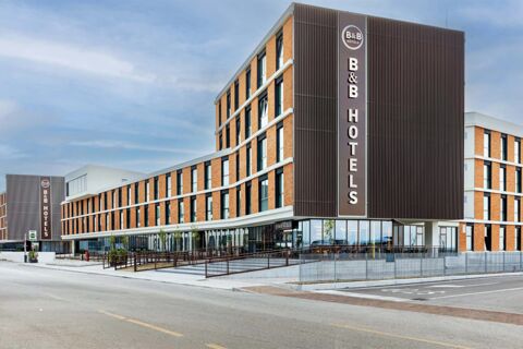 Modern curved low-rise building with brown and white exterior and large vertical sign displaying B&B Hotels at B&B Hotel Venezia Laguna
