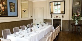 Elegant dining room at Hotel du Vin Tunbridge Wells with a long white tablecloth, wine bottles, glassware, and upholstered chairs