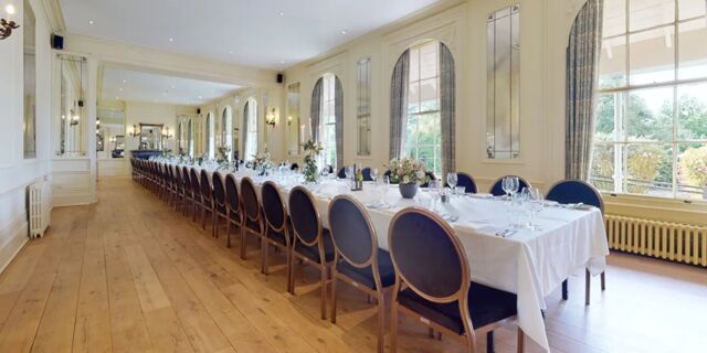 Long dining table with wooden chairs, set with white tablecloth and glassware in a room at Hotel du Vin Tunbridge Wells