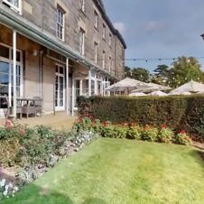 Outdoor garden area with trimmed hedges, flower beds, patio furniture, and umbrellas at Hotel du Vin Tunbridge Wells