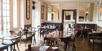 Dining room with wooden tables and chairs, set with glassware and cutlery, at Hotel du Vin Tunbridge Wells