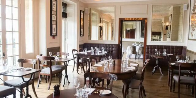 Dining room with wooden tables and chairs, set with glassware and cutlery, at Hotel du Vin Tunbridge Wells