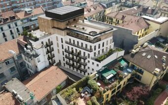 Aerial view of modern white Hotel Calimala with rooftop gardens solar panels and surrounding residential buildings with terracotta roofs
