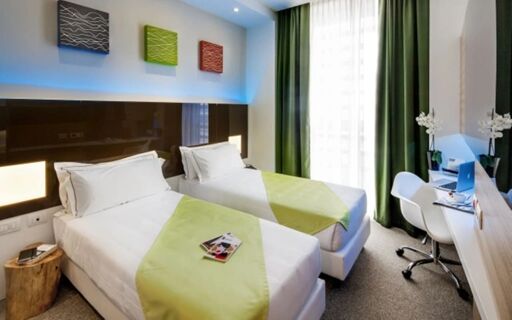 Two single beds with white and green bedding in a bright room with green curtains at Hotel degli Arcimboldi