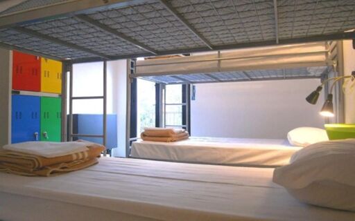 Bunk beds with folded towels and colorful lockers in a clean dormitory room at Hostel Colours
