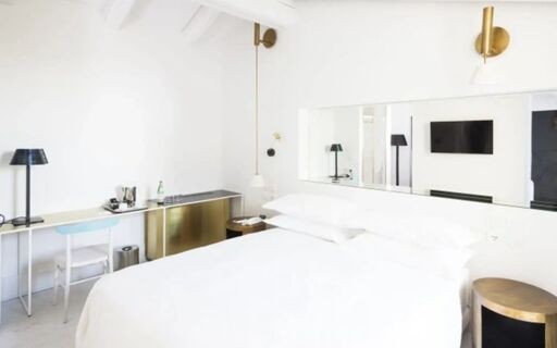 Bright white hotel room at Senato Hotel Milano with a large bed, wall-mounted TV, desk, and minimalist decor
