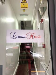 Glass door with a white sign displaying Leman House in blue and red script in a narrow corridor with CCTV in operation sign above