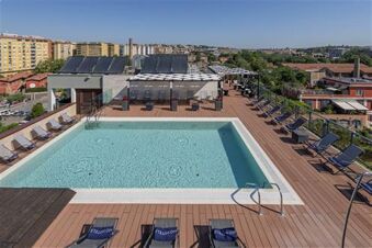 Outdoor swimming pool with lounge chairs and solar panels on the rooftop of H10 Roma Citt&agrave; hotel in Rom