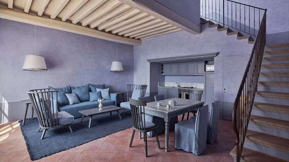 Living and dining area with blue-gray furniture, dining table set, kitchen, and staircase at Podere San Filippo