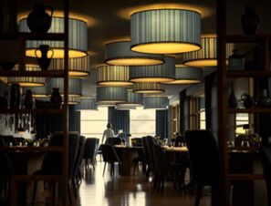 Dimly lit dining area of COMO Alpina Dolomites with hanging cylindrical lamps and a person near large windows