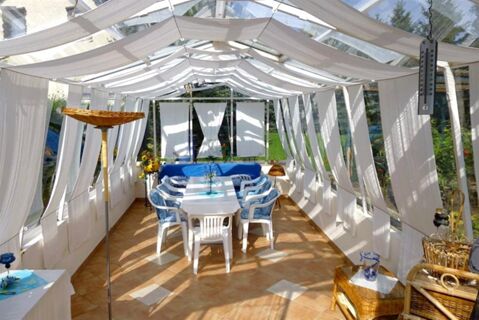 Dining area at Privatpension Flemminger Hof with white table, blue cushioned chairs, wicker furniture, and sheer curtains on windows and ceiling