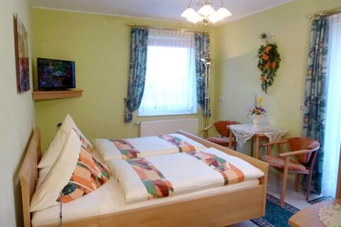 Gem&uuml;tliches G&auml;stezimmer mit zwei Einzelbetten, Tisch und St&uuml;hlen sowie Dekoration im Privatpension Flemminger Hof.