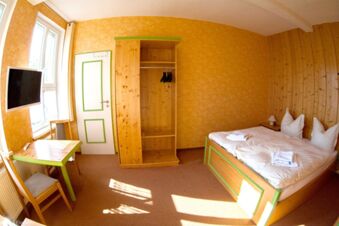 Helles Hotelzimmer mit Holzm&ouml;beln, Doppelbett, Tisch und Fernseher im Sandgut Mihla Gasthof und Hotel, gem&uuml;tlich und einladend.