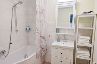 Hell gestaltetes Badezimmer mit Badewanne, Dusche, Waschbecken und wei&szlig;en Handt&uuml;chern im Sandgut Mihla Gasthof und Hotel.