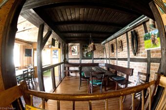 Rustikaler Gastraum mit Holzb&auml;nken und Tischen sowie sichtbaren Balken im Sandgut Mihla Gasthof und Hotel.