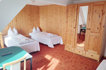 Gem&uuml;tliches Zimmer mit zwei Einzelbetten, Holzvert&auml;felung und Kleiderschrank im Sandgut Mihla Gasthof und Hotel, hell und einladend.