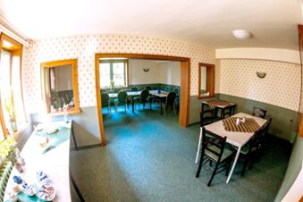 Innenansicht eines rustikal eingerichteten Gastraums mit Tischen und St&uuml;hlen im Sandgut Mihla Gasthof und Hotel, der eine gem&uuml;tliche Atmosph&auml;re bietet.